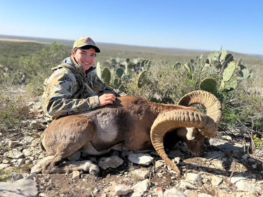 Brody Jackson with a harvested ram in Texas terrain, demonstrating hands-on field knowledge and ethical exotic hunting practices.
