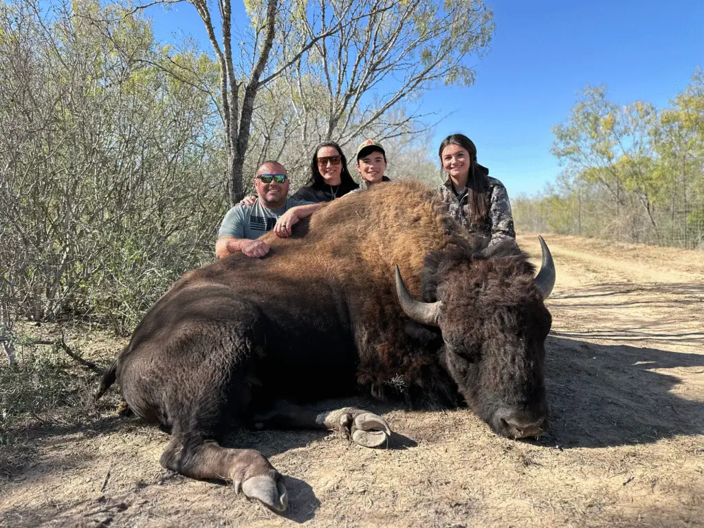 Group photo with Brody Jackson and family posing behind a harvested American bison during a guided exotic hunt in Texas.