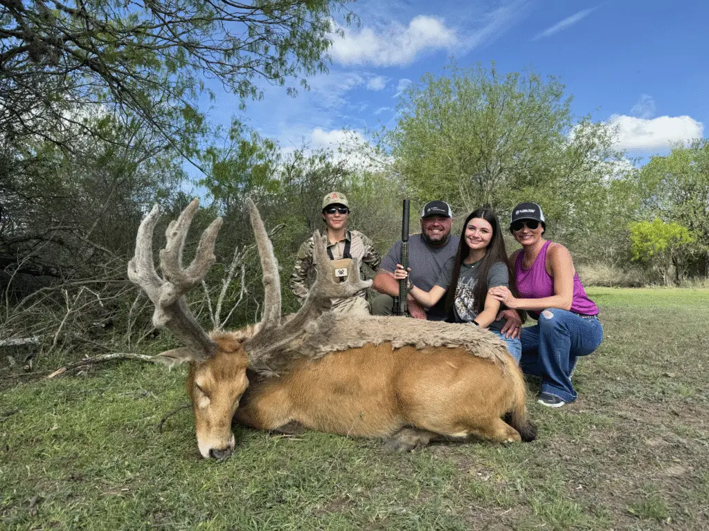 Brody Jackson and family posing with a harvested Père David’s deer, showcasing a family-friendly guided hunting experience in Texas.